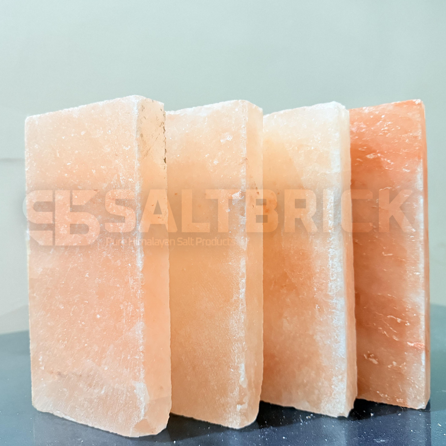 Four Himalayan salt blocks stacked on a reflective surface with 'SALT BRICK' branding.